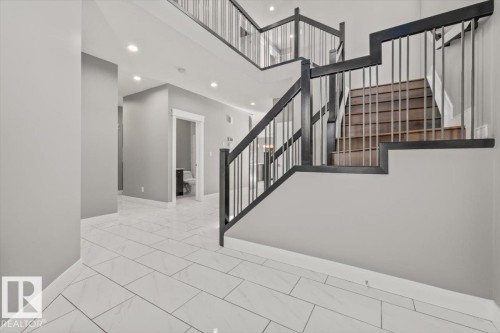 Two-story foyer featuring tile flooring, recessed lighting, and a multi-level staircase with dark wood-finish handrails and metal balusters - 1090 Armitage Crescent Sw, Edmonton, AB 