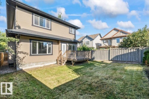 Expansive backyard featuring a wood deck, wood privacy fence, and a manicured lawn - 1090 Armitage Crescent Sw, Edmonton, AB 