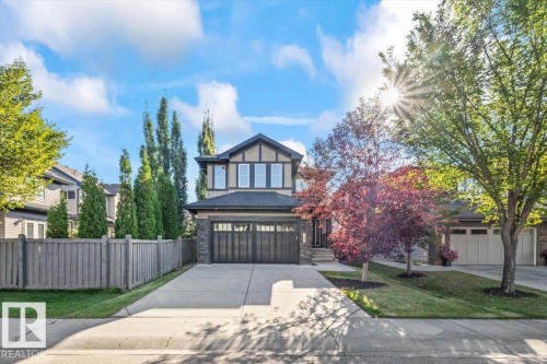 Two-story residence featuring a large driveway, a stone and stucco facade, a two-car garage, and mature landscaping - 1090 Armitage Crescent Sw, Edmonton, AB 