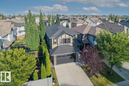 Two-story residence with attached garage, concrete driveway, front yard landscaping, and mature trees - 1090 Armitage Crescent Sw, Edmonton, AB 