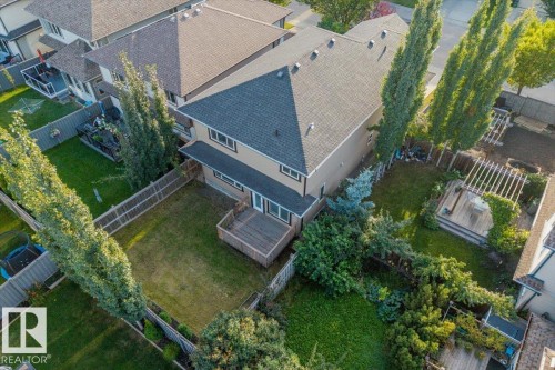 Expansive backyard with a wooden deck, mature trees, and a pergola-covered patio area - 1090 Armitage Crescent Sw, Edmonton, AB 