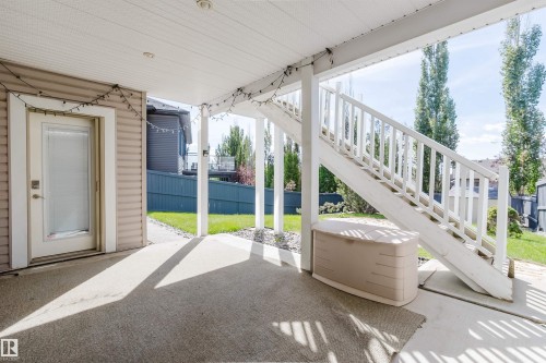 Covered patio with a concrete surface, white painted railings, and an exterior door with a frosted glass panel - 3412 Macneil Link Nw, Edmonton, AB 