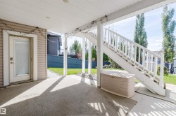 Covered patio with a concrete surface, white painted railings, and an exterior door with a frosted glass panel - 