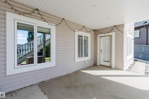 Covered patio area with concrete surfacing, multiple windows, and a glass-paneled door - 3412 Macneil Link Nw, Edmonton, AB 