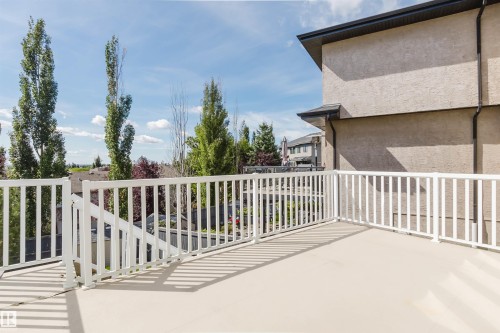 Spacious outdoor deck with white railing, light-toned flooring, and stucco exterior - 3412 Macneil Link Nw, Edmonton, AB 