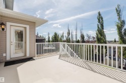 Exterior balcony with white railings, a tan surface, and a glass-paneled door - 