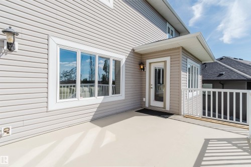 Exterior siding featuring a window with white trim, a glass-paneled door, and a white deck railing - 3412 Macneil Link Nw, Edmonton, AB 