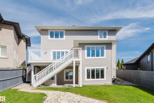 Exterior featuring horizontal siding, multiple large windows, and a raised deck with white railings and stairs - 3412 Macneil Link Nw, Edmonton, AB 