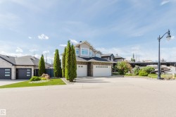 Two-story exterior with stone and siding facade, two attached garages, and a paved driveway - 
