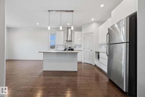 Kitchen featuring wood-finish flooring, a central island, stainless steel appliances, white cabinetry, and recessed lighting - 8952 81 Avenue Nw, Edmonton, AB 