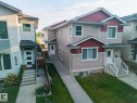 Two-story residence featuring light-toned siding with red accent panels, multiple windows, and a concrete pathway - 8952 81 Avenue Nw, Edmonton, AB 