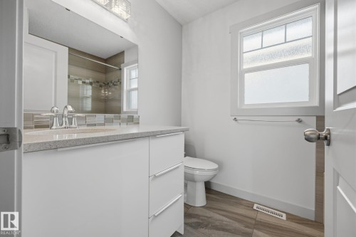 Contemporary bathroom featuring a modern vanity with integrated sink, stone-look countertop, and chrome faucet - 8952 81 Avenue Nw, Edmonton, AB 
