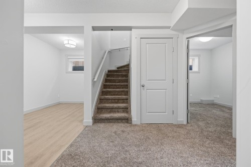 Neutral-toned carpeting, wood-finish flooring, white trim, and a contemporary ceiling light fixture - 8952 81 Avenue Nw, Edmonton, AB 