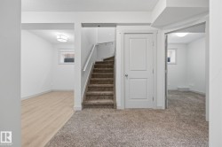 Neutral-toned carpeting, wood-finish flooring, white trim, and a contemporary ceiling light fixture - 