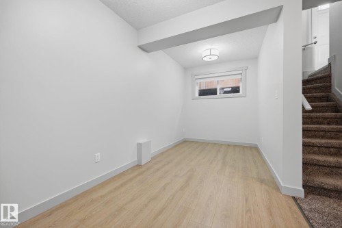 Wood-finish flooring, ceiling-mounted light fixture, white walls, and a window with white trim - 8952 81 Avenue Nw, Edmonton, AB 
