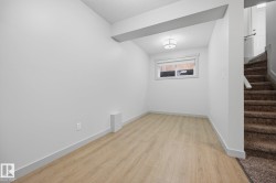 Wood-finish flooring, ceiling-mounted light fixture, white walls, and a window with white trim - 