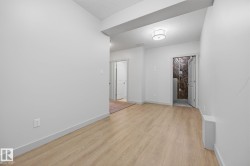 Light wood-finish flooring, white walls, and a flush-mount ceiling light - 