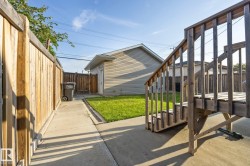 Wood privacy fencing, concrete pathway, green lawn, exterior siding, and a wooden deck structure - 