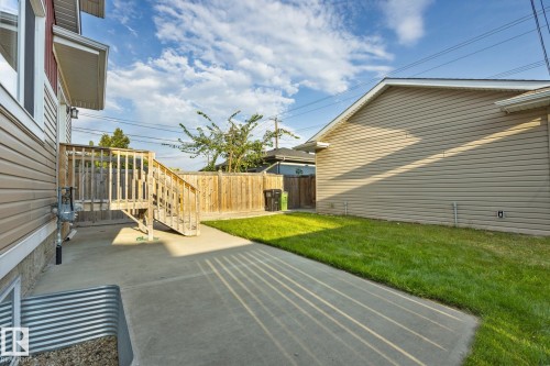 Concrete patio with wooden stairs, surrounded by a wood privacy fence and a manicured lawn - 8952 81 Avenue Nw, Edmonton, AB 