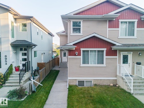 Two-story residence with a red and beige siding exterior, covered entry, and white railing on concrete steps - 8952 81 Avenue Nw, Edmonton, AB 