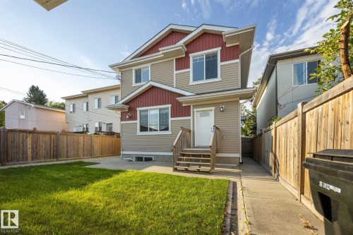 Two-story exterior with beige siding and red accents, featuring a front entry deck and walkway - 8952 81 Avenue Nw, Edmonton, AB 