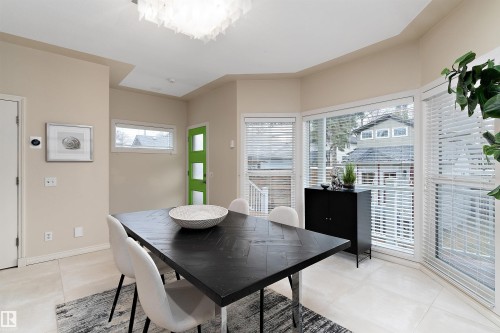 Recessed ceiling lighting, large bay window, light-toned flooring, contemporary chandelier, and a vibrant green door - 9654 100 Street Nw, Edmonton, AB 