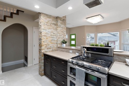 Modern kitchen featuring stainless steel range, light-toned countertops, and dark wood-finish cabinetry - 9654 100 Street Nw, Edmonton, AB 