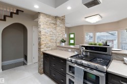 Modern kitchen featuring stainless steel range, light-toned countertops, and dark wood-finish cabinetry - 
