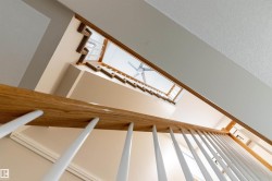Staircase with wood-finish handrail, white balusters, and carpeted treads - 