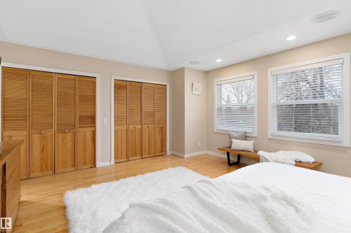 Hardwood flooring, two sets of louvered bifold closet doors, two windows with blinds, recessed ceiling lighting, and a sloped ceiling - 9654 100 Street Nw, Edmonton, AB 