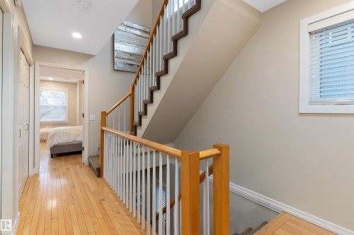 Hardwood flooring, light neutral wall color, staircase with carpeted treads and wood handrail, recessed lighting, and a window with blinds - 9654 100 Street Nw, Edmonton, AB 
