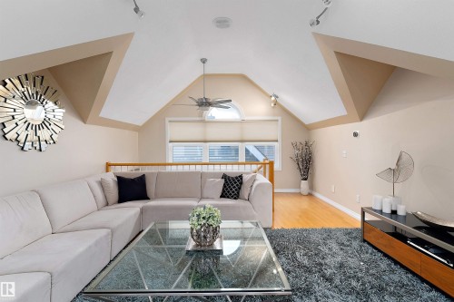 Vaulted ceiling with track lighting, ceiling fan, natural wood flooring, and arched window with blinds - 9654 100 Street Nw, Edmonton, AB 