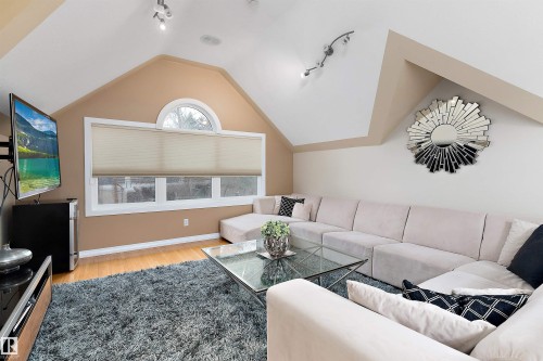 Sloped ceilings with track lighting, multiple windows including an arched transom, and wood-finish flooring - 9654 100 Street Nw, Edmonton, AB 
