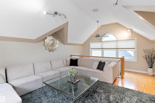 Vaulted ceiling with track lighting, hardwood flooring, ceiling fan, and arched window with blinds - 9654 100 Street Nw, Edmonton, AB 
