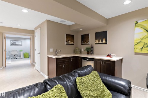 Wet bar featuring dark wood-finish cabinetry, a single basin sink, and a built-in beverage refrigerator - 9654 100 Street Nw, Edmonton, AB 