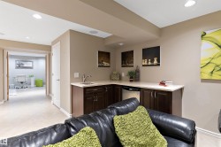 Wet bar featuring dark wood-finish cabinetry, a single basin sink, and a built-in beverage refrigerator - 
