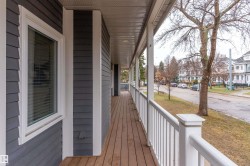 Expansive covered porch featuring wood-finish decking, white railings, and durable siding - 