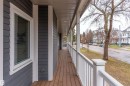 Expansive covered porch featuring wood-finish decking, white railings, and durable siding - 9654 100 Street Nw, Edmonton, AB 