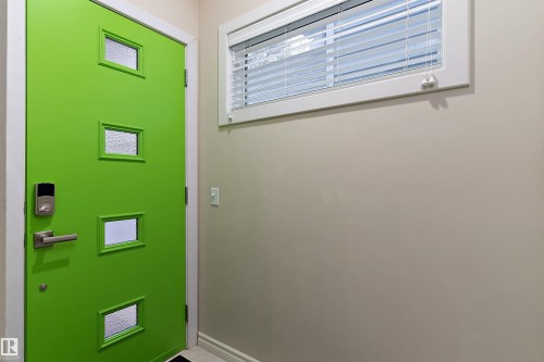 Vibrant green door featuring multiple frosted glass panels, brushed metal door hardware, and an electronic keypad entry - 9654 100 Street Nw, Edmonton, AB 