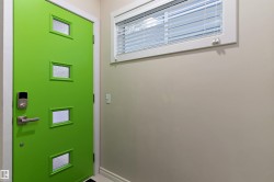 Vibrant green door featuring multiple frosted glass panels, brushed metal door hardware, and an electronic keypad entry - 