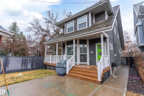 Two-story exterior with horizontal siding, covered porch, wood-finish steps, and a bright green entry door - 9654 100 Street Nw, Edmonton, AB 
