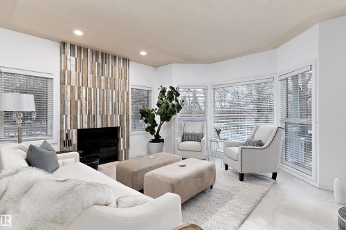 Recessed ceiling lighting, a fireplace with a wood-panel surround, and large windows with horizontal blinds - 9654 100 Street Nw, Edmonton, AB 