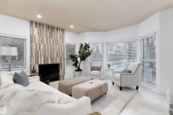 Recessed ceiling lighting, a fireplace with a wood-panel surround, and large windows with horizontal blinds - 