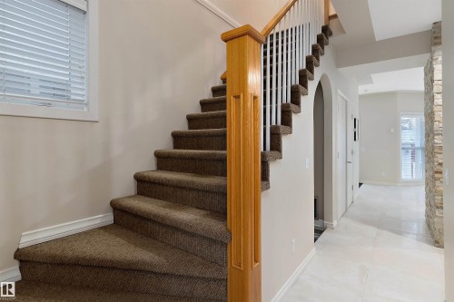 Carpeted staircase with wood newel post and white balusters - 9654 100 Street Nw, Edmonton, AB 