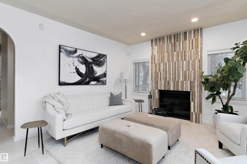 Recessed lighting, wood-look fireplace surround, built-in fireplace, two windows with blinds, and an arched entryway - 9654 100 Street Nw, Edmonton, AB 