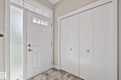 Entryway featuring a paneled door with transom window, frosted sidelight, and bi-fold closet doors - 