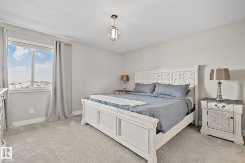 Neutral wall paint, light-toned carpeting, and a double window with a water backdrop - 2096 Redtail Common Nw, Edmonton, AB 