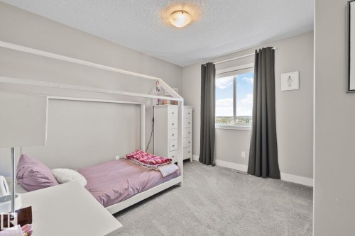 Carpeted room featuring neutral wall tones, a large window with privacy coverings, and a ceiling-mounted light fixture - 2096 Redtail Common Nw, Edmonton, AB 