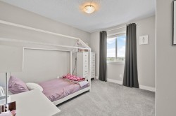 Carpeted room featuring neutral wall tones, a large window with privacy coverings, and a ceiling-mounted light fixture - 