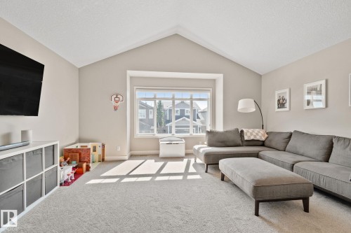 Vaulted ceiling with a large picture window, neutral wall tones, and plush carpet flooring - 2096 Redtail Common Nw, Edmonton, AB 